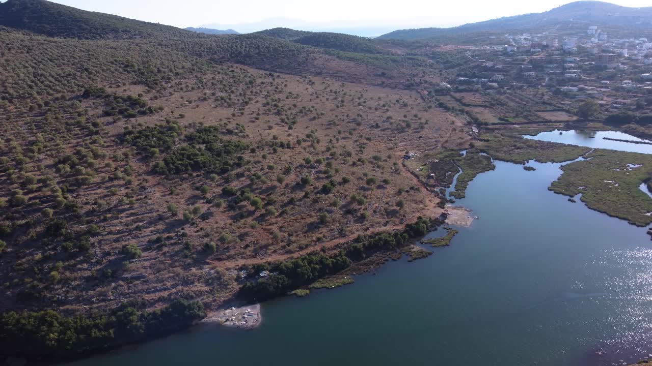 Tomada aérea panorâmica lateral sobre o Lago Butrint com Ksamil ao fundo, Albânia
