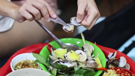 hands removing clam shells over a fresh salad