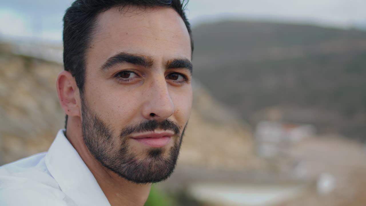 hombre guapo sonriendo cámara en la playa de primer plano. hombre posando en la orilla del océano vertical