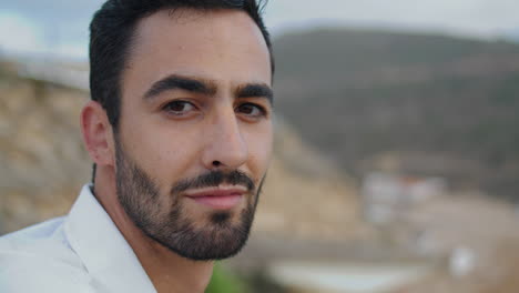 handsome guy smiling camera at beach closeup. man posing at ocean shore vertical