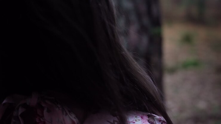 Donna con lunghi capelli scuri in un abito floreale in una foresta