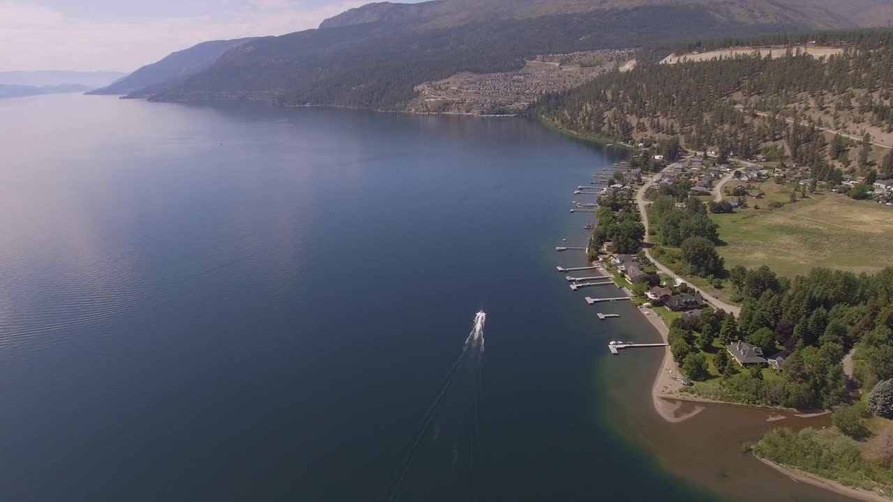 호숫가의 작은 마을을 지나는 보트의 공중선을 따라가다