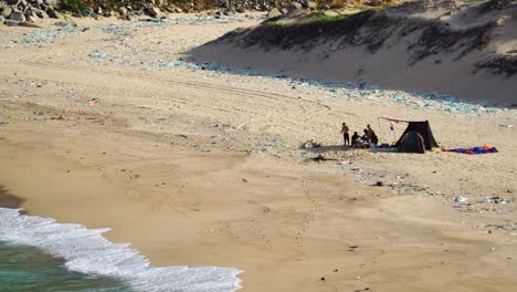 la gente local disfruta de las vacaciones de verano en la playa contaminada de binh, colgada de una tienda de campaña.