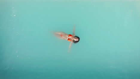 aerial top down close up view beautiful girl in red bikini float on turquoise water on holiday relaxing vacation. crystal clear turquoise sea. vacation travel at paradise