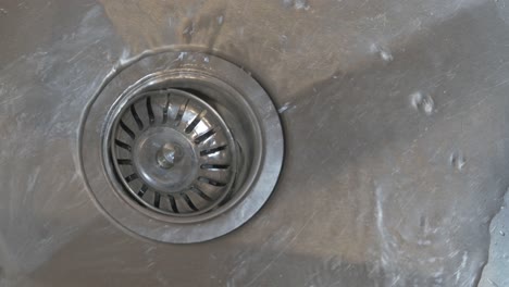 running tap water flowing down plug hole or drain