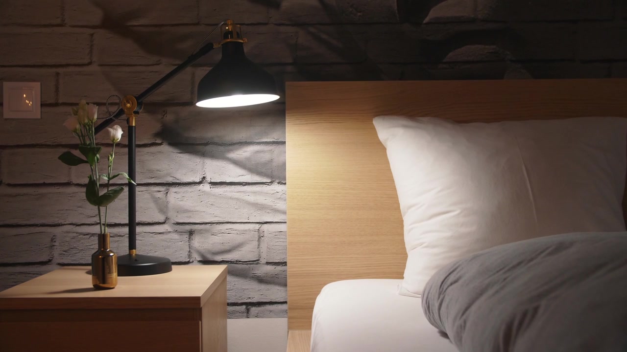 Koselig og rent nattbord med blomster og en moderne, avslappende lampe