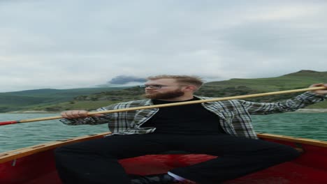 man rowing a boat on a mountain lake