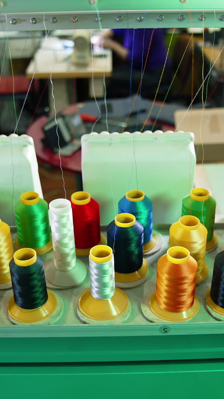 Industrial machines with colorful sewing thread. Rows spools of thread of different colors in the industrial sewing machine. Vertical video
