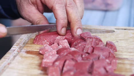 close up of a person chopping sausage on a cutting board