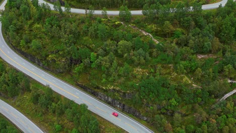 Antena-A-Lo-Largo-De-Una-Carretera-Sinuosa-Con-Un-Solitario-Coche-Rojo-Cerca-De-Hjelledalen,-Noruega