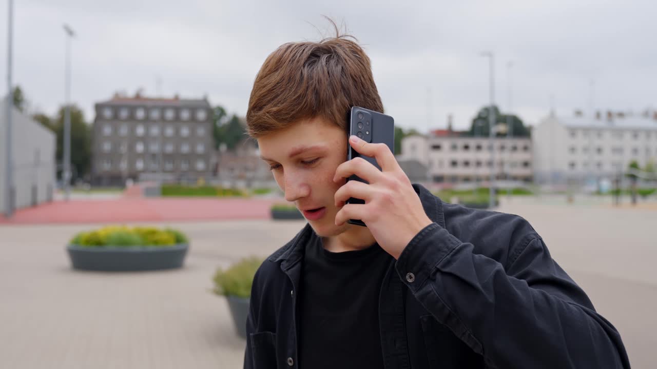 Young man talking on a mobile phone while standing in a modern city square