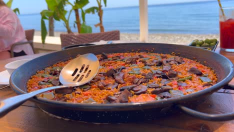 plato tradicional español de paella con verduras en un restaurante junto al mar, sabroso arroz cocido con verduras, aceitunas verdes tapas, marbella españa, tiro de 4k