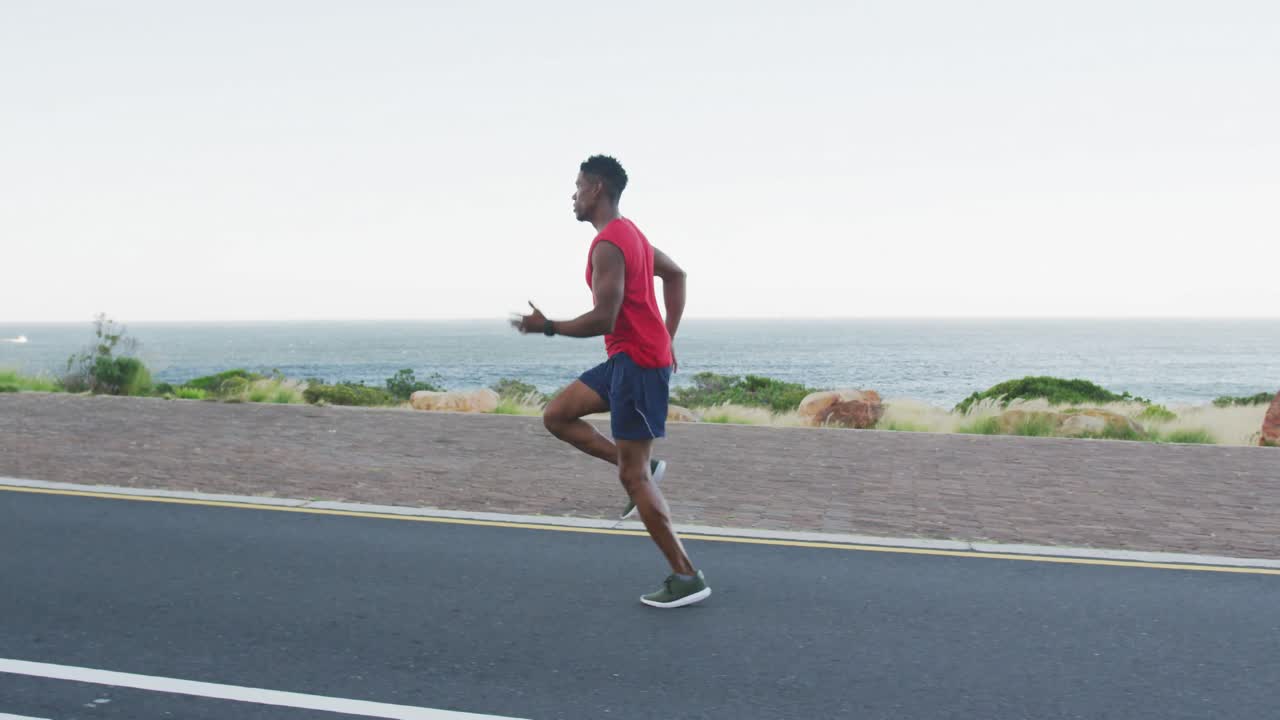 아프리카계 미국인 남자가 야외에서 연안 도로에서 뛰고 있습니다.