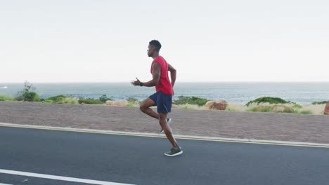 african american man exercising outdoors running on a coastal road