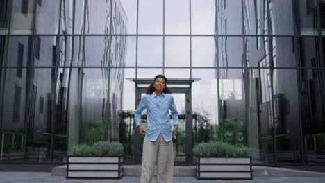 Attractive-office-worker-posing-keeping-hands-in-pockets-on-modern-city-street.