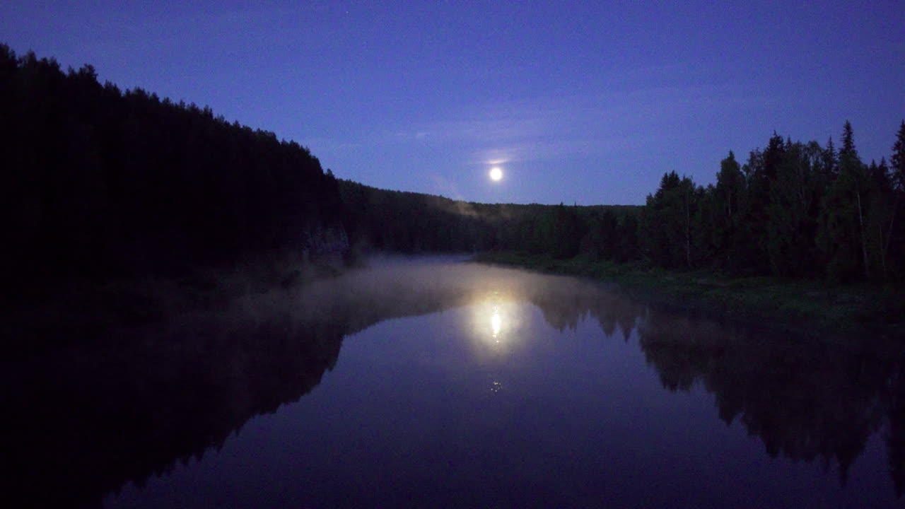 Reflexos de rio iluminados pela lua em uma floresta nebulosa