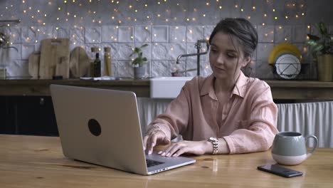 mujer trabajando en una computadora portátil en una cocina acogedora