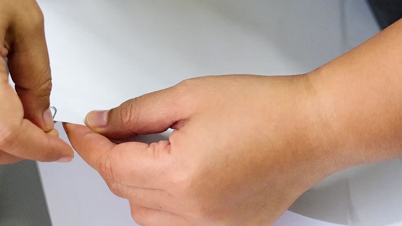 Close-up of hands folding and aligning sheets of white paper on a desk.