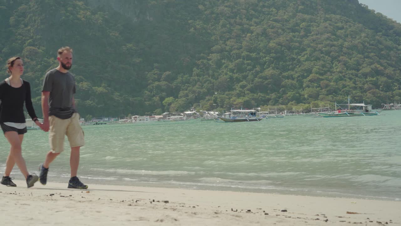 필리핀 엘니도 의  모래 해변 에서 산 을 배경 으로 모험 을 하고 있는 관광 부부 - 넓은