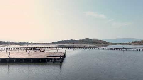 People-walking-on-a-wooden-bridge-above-the-sea-during-sunset-and-taking-pictures-on-a-platform