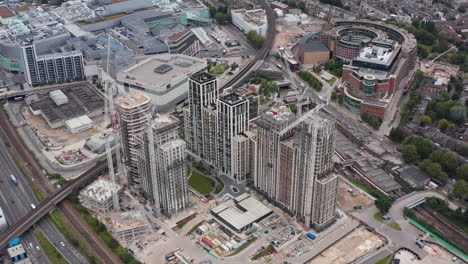 Slide-and-pan-footage-of-tower-cranes-on-construction-site-of-apartment-buildings-complex.-Aerial-view-of-modern-city-district.-London,-UK