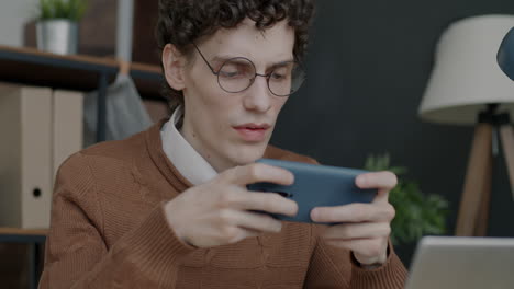 young man playing mobile games in an office
