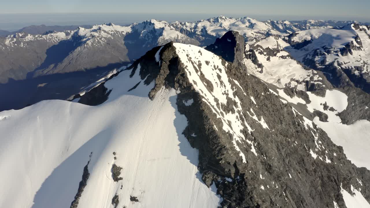 enorme montaña con roca y nieve en la cima entre una espectacular cadena montañosa muy por encima de los valles en nueva zelanda durante el amanecer