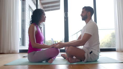biracial couple doing yoga and meditating at home, in slow motion