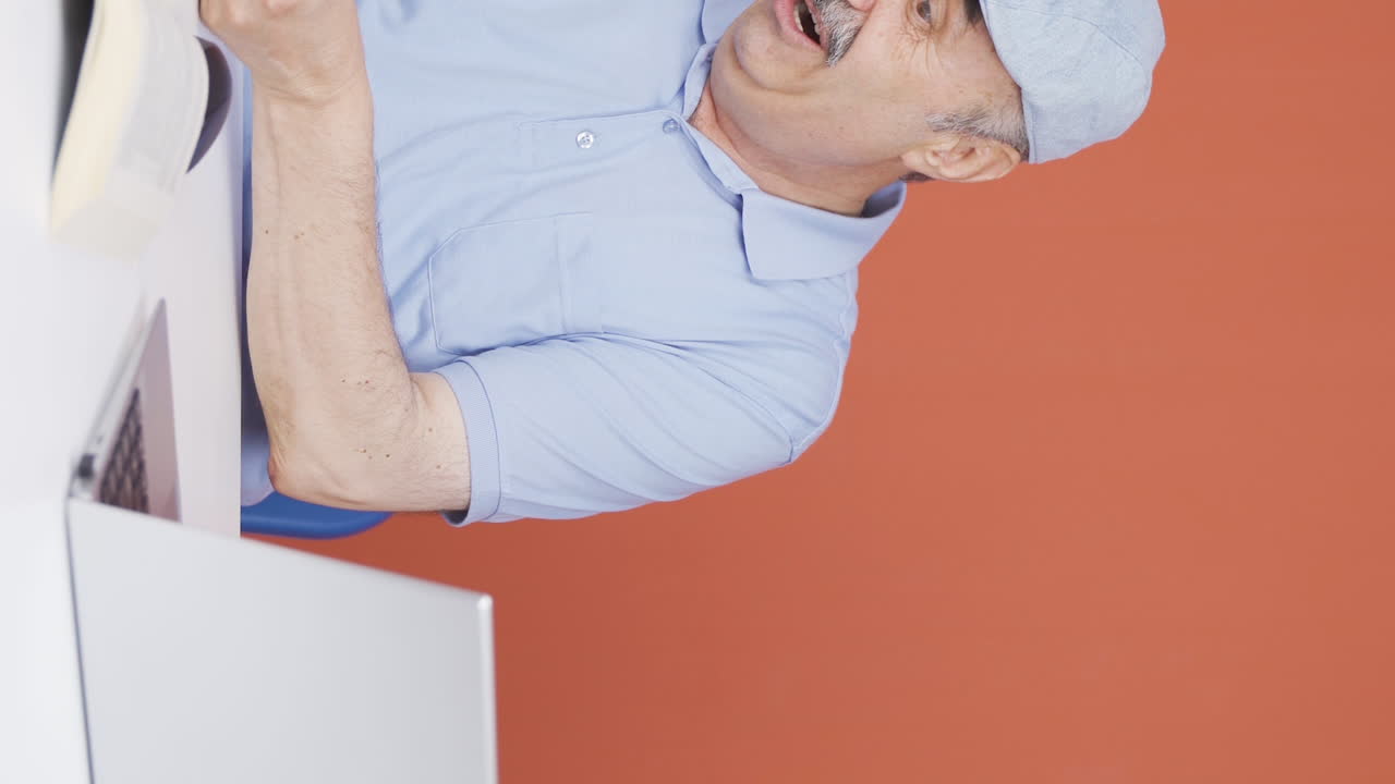 노인이 행복한 표정으로 노트북에서 일하는 수직 비디오.