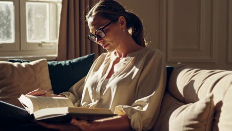 mujer leyendo un libro en un sofá