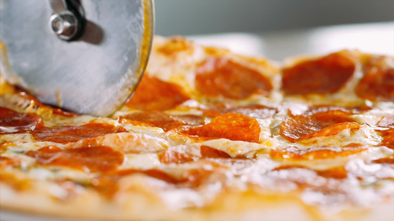 롤러 피자 커터 를 사용 하여 살라미 피자를 조각 으로 잘라내는 여자 의 손