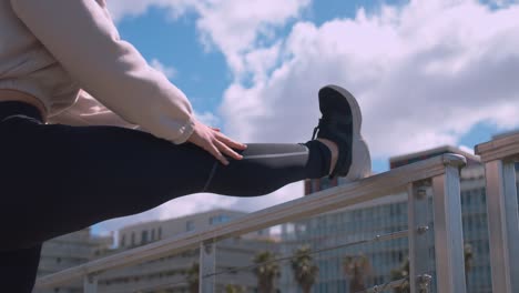 a girl in a tracksuit is doing exercise by stepping on a railing