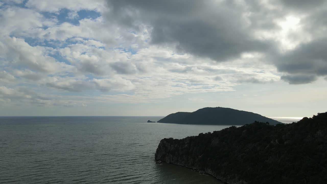 imágenes aéreas deslizantes a la izquierda que revelan la silueta de una montaña de piedra caliza, una isla, un hermoso horizonte, un cielo azul y nubes de lluvia