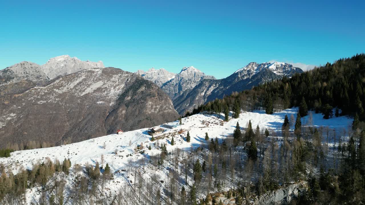 Filmato aereo realizzato con drone sopra il Rifugio Pradut, Italia: giornata di dicembre limpida con montagne soleggiate senza neve e pendii ombreggiati coperti di neve. Perfetto per progetti invernali, alpini e naturalistici