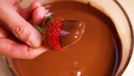 strawberry dipped in melted chocolate by hand