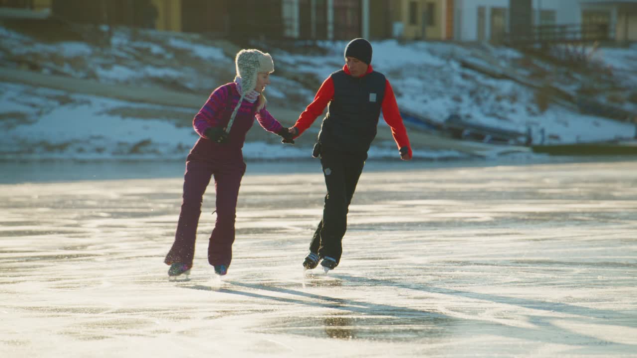 En dejlig vinterdag på isen: To personer står på skøjter sammen og omfavner naturens skønhed og spændingen ved at stå på skøjter og skaber gode minder i et smukt frossent landskab