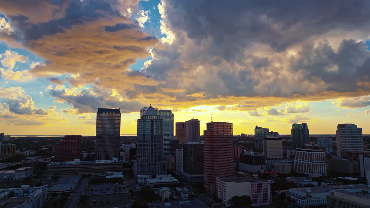 Glowing evening sunset of the Tampa skyline with warm clouds, aerial tracking to the left, establishing shot