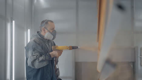 a professional painter in production in slow motion paints parts