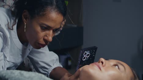 woman doctor examining patient's face with mobile phone