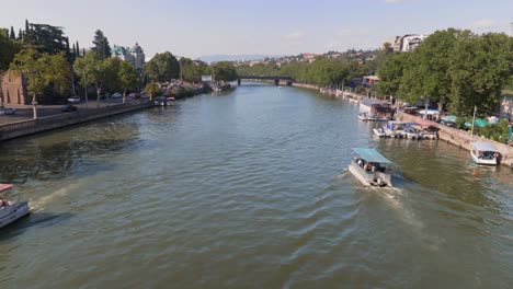 Ship-transportation-on-Kura-river-in-Tbilisi-city-on-sunny-day,-Georgia