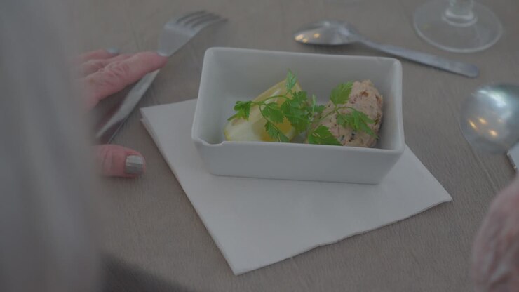 Detailní záběr na ruce seniora s pokrmem z luxusní restaurace