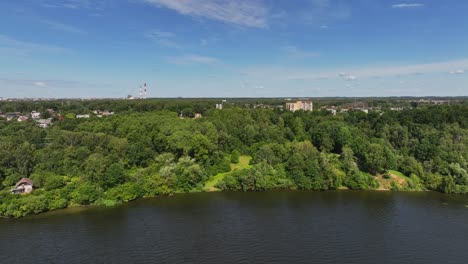 Panoramablick:-Das-Seeufer-Ist-Mit-Großen-Grünen-Bäumen-Bedeckt,-Und-Hinter-Den-Bäumen-Befinden-Sich-Wohn--Und-Industriegebäude