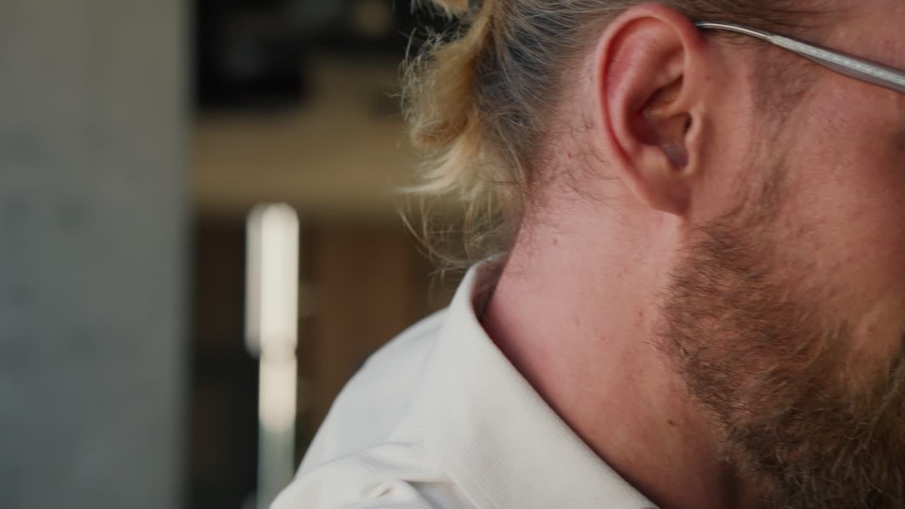 disparando de cerca, un hombre rubio con gafas se pone una chaqueta marrón, es ayudado por su colega en una chaqueta azul. comienzo del día de trabajo en la oficina