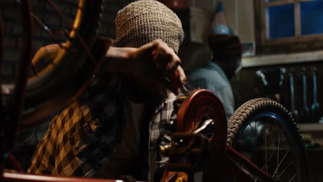 man repairing a vintage red bicycle in a garage