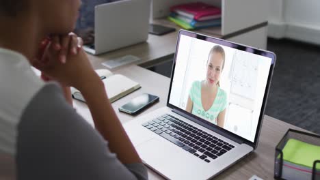 African-american-businesswoman-sitting-at-desk-using-laptop-having-video-call-with-female-colleague