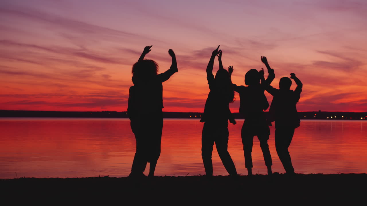 해변에서 해가 지면 친구들이 춤을 춘다