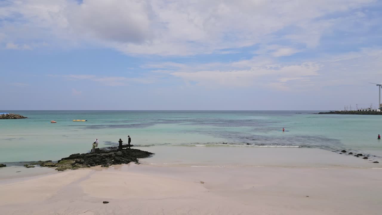 Stunning drone view of Woljeong Beach's pristine shores, a tranquil oasis on beautiful Jeju Island, with a unique view of Wind Turbines in right on the waters edge