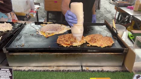 street food vendors skillfully spread the mayonnaise onto the fried pancake