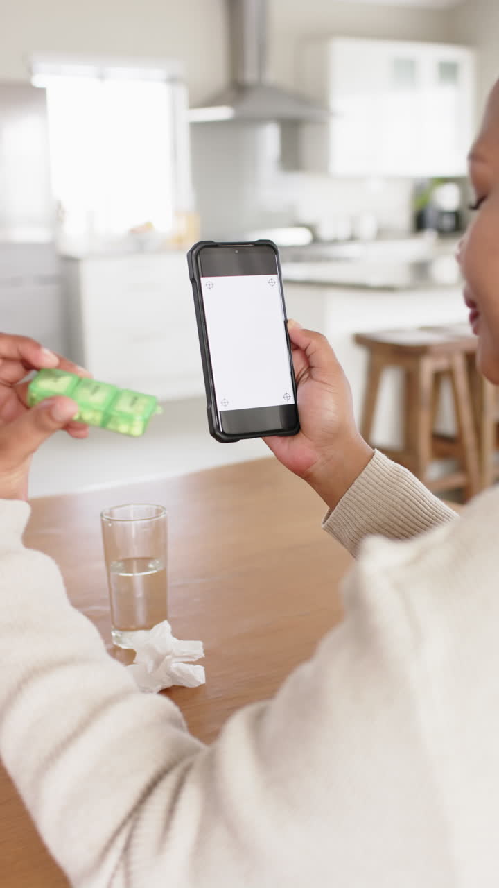 Vertical video of african american woman with medication using phone with copy space, slow motion