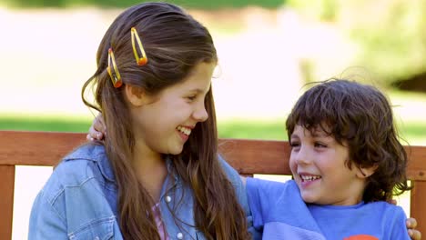 brother and sister laughing together on park bench